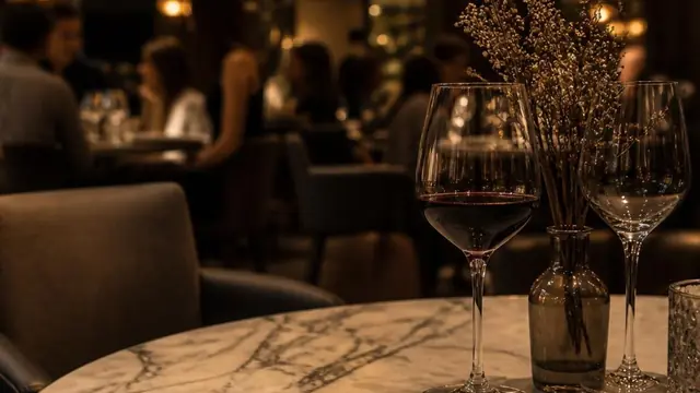 Marble dining table in a busy restaurant setting with wine glasses